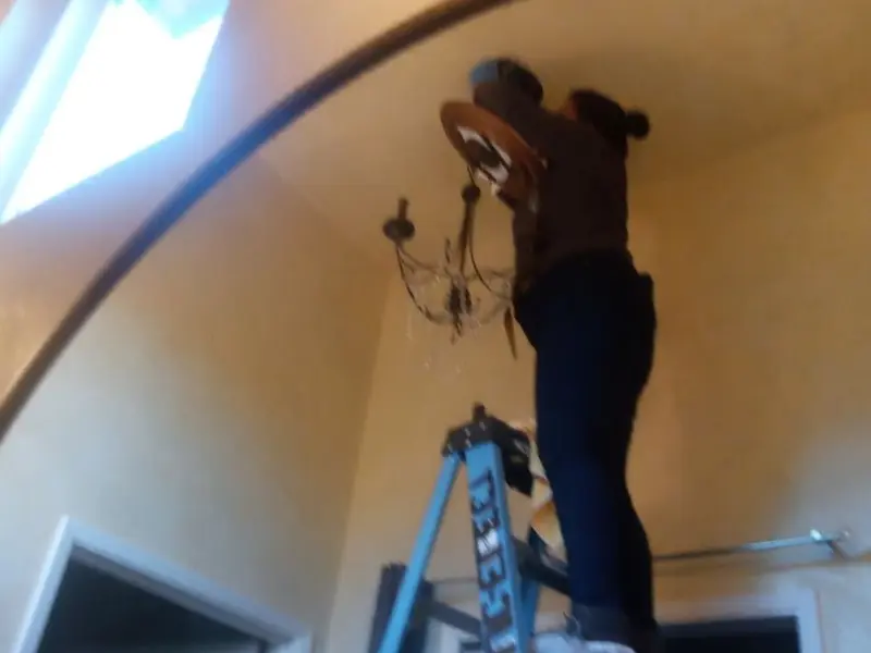 Electrician installing a chandelier in a Wellington residence